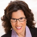 Headshot of a smiling women with dark hair and wearing dark framed classes