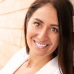 Headshot photo of smiling woman with long straight dark brown hair
